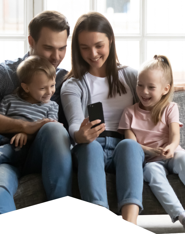 Happy young parents sit on couch with little children have fun using smartphone together, smiling caucasian family with small kids relax on sofa in living room watch funny videos on cellphone