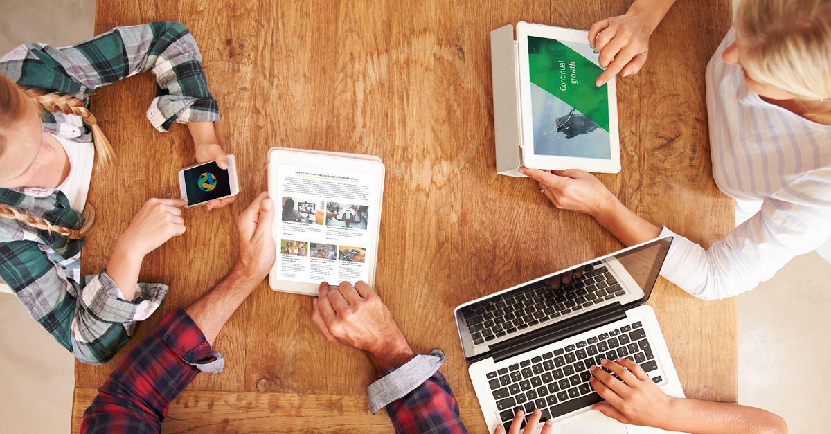 Group of friends at table using a variety of devices