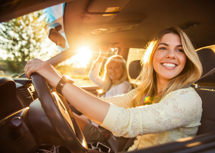 Friends Driving Two blonde women driving a car and smiling at the camera