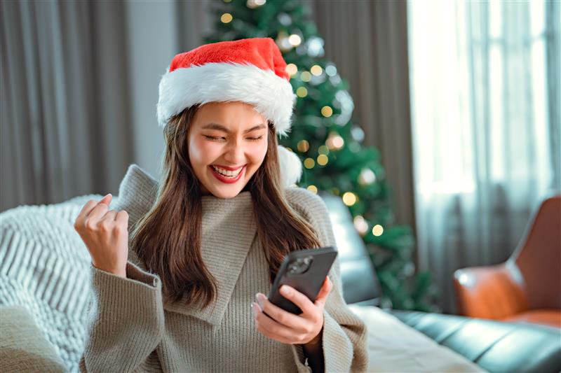a woman wearing a santa hat and holding a phone